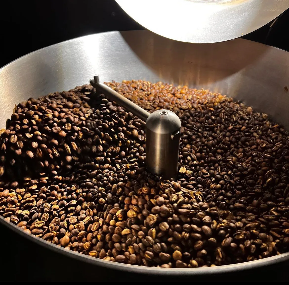 Freshly roasted coffee beans turning in the drum of the Black Honey roaster